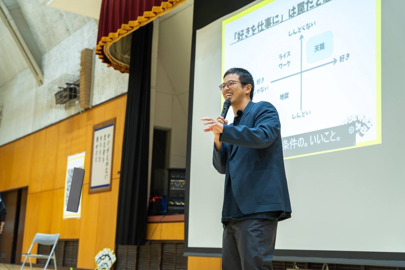 会場のスクリーンを背に、マイクを持って講演する川人佑太